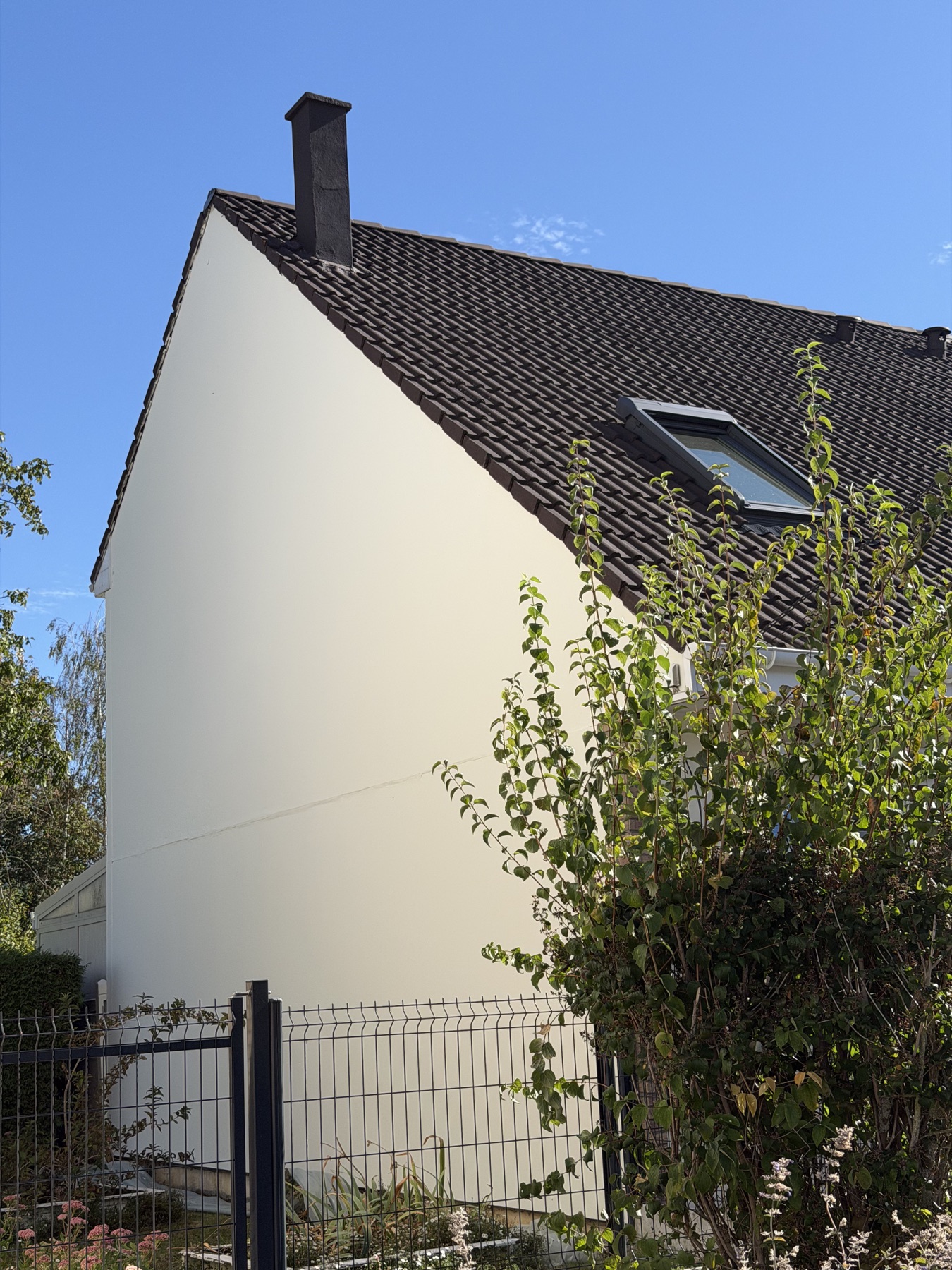 Pignon clair, toiture en tuiles et cheminée d’une maison